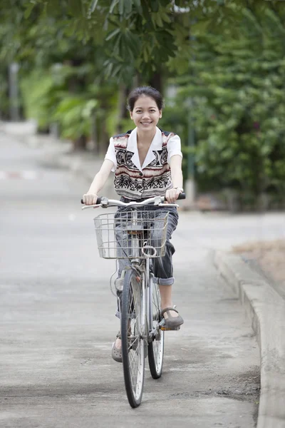Girl riding bicycle in home village street — Stock Photo, Image