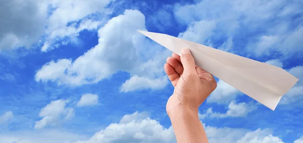 Mão jogando avião de papel para o céu azul — Fotografia de Stock