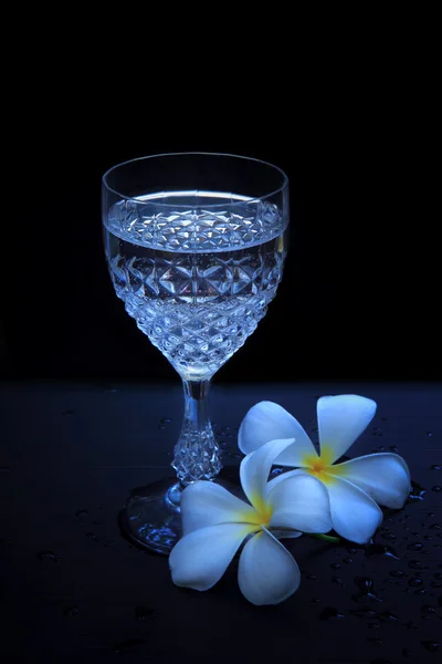 Agua potable en el vaso con una flor en un lado — Foto de Stock