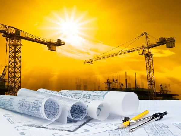 Architect plan on working table with crane and building construction background — Stock Photo, Image