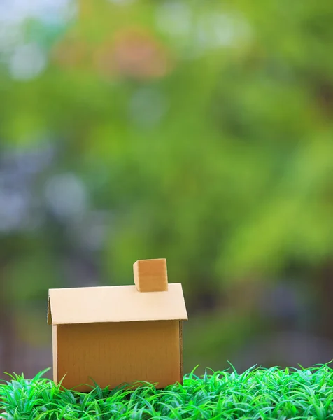 Изготовление дома из старой бумажной коробки, лежащей на зеленой траве; — стоковое фото