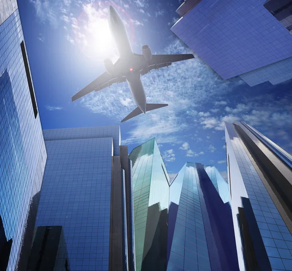 Passenger plane flying ove rmodern office building against blue — Stock Photo, Image