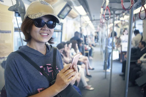 kadın gök yüzü tren ile akıllı telefon elinde şehir hayatı ve Tema seyahat için kullanın