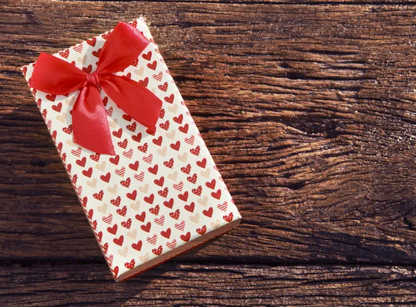 Coração mancha presente caixa com fita vermelha na textura de madeira velha — Fotografia de Stock