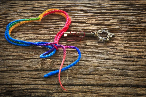 Forma de coração de fio colorido e chave na madeira texturizado uso de fundo para sinal de amor no dia dos namorados e resumo do sinal de amor — Fotografia de Stock