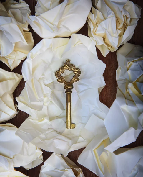 Golden key on crumpled paper on wood table seem some successfull — Stock Photo, Image