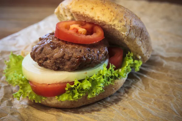 Nahaufnahme von Schinken-Burger und Brötchen mit Tomatenzwiebeln und grünem Gemüse — Stockfoto