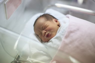 Doğumhanedeki battaniyede uyuyan yeni doğmuş bir bebek.