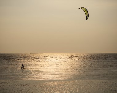 Adam uçurtma surving ayakta akşam güneşi karşı deniz suyu ile