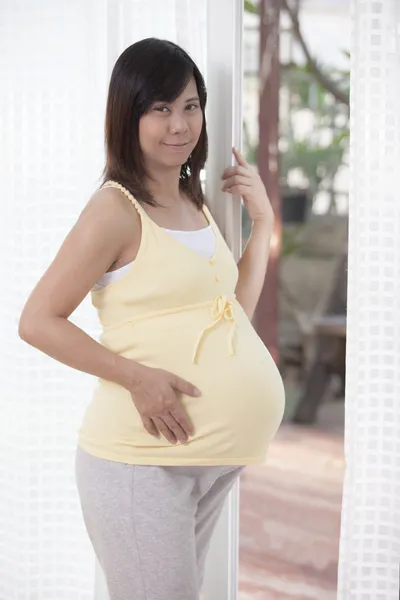 Nő terhes álló mellett saját ajtót, és keresi, hogy kamerát — Stock Fotó