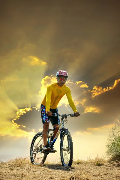 Joven hombre montando bicicleta de montaña mtb en la duna de tierra contra el cielo oscuro en el fondo de la noche uso para el deporte de ocio y actividades al aire libre tema —  Fotos de Stock