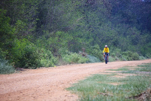 Joven montando bicicleta de montaña en carretera polvorienta uso para actividades heladas y ciclistas —  Fotos de Stock