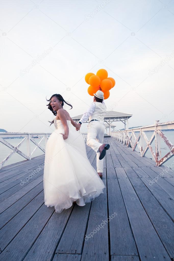 Asian groom and bride in wedding suit take photo for marriage ceremony picture on location