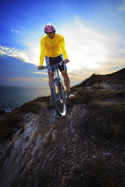Joven hombre montando bicicleta de montaña mtb en la duna de tierra contra el cielo oscuro —  Fotos de Stock