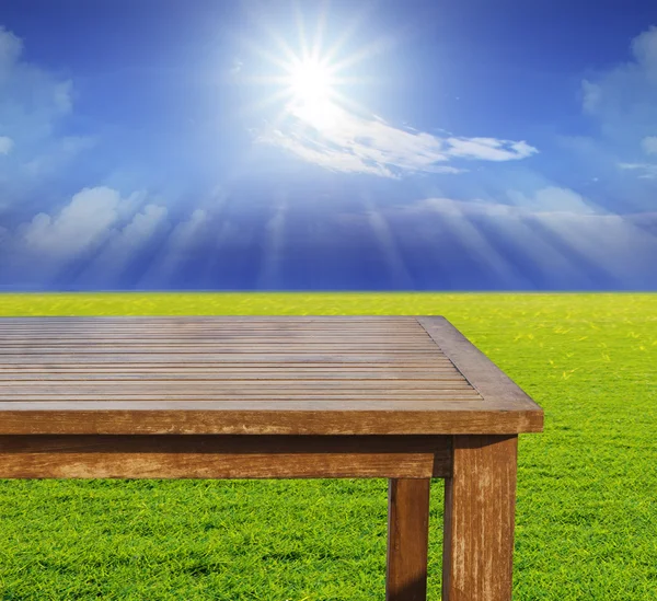Tavolo in legno vuoto spazio libero su prato verde contro il sole — Foto Stock