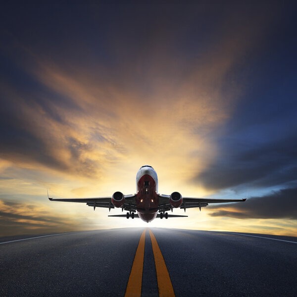 Пассажирский самолет взлетает с взлетно-посадочных полос на фоне прекрасного заката
