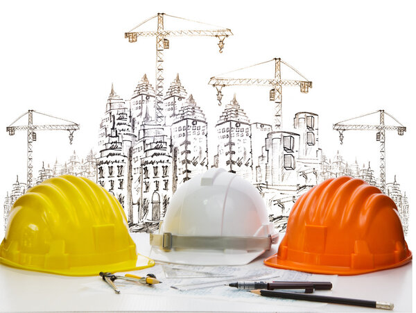 Safety helmet on engineer working table against sketching of building construction and high crane