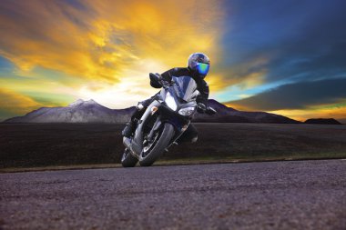 genç adam asfalt yolun eğri ile kırsal yılında motosiklet sürme ve