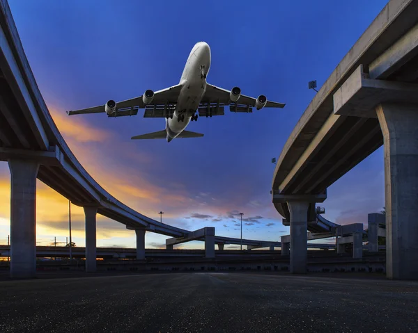 Пассажирский реактивный самолет, пролетающий над транспортным наземным мостом, использует это изображение для темы воздушного и наземного транспорта — стоковое фото