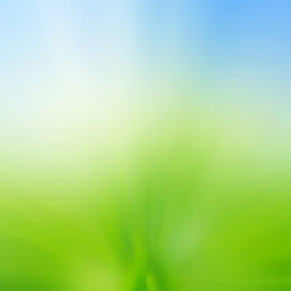 Abstrakt oskärpa bakgrund av grönt gräs fält och blå himmel ovan — Stockfoto