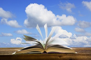 ahşap masa eski kitap sayfasında Özet eğitim ve fikir yaratıcı okul nesnesi için güzel mavi gökyüzü karþý uçan kitap sayfası açın