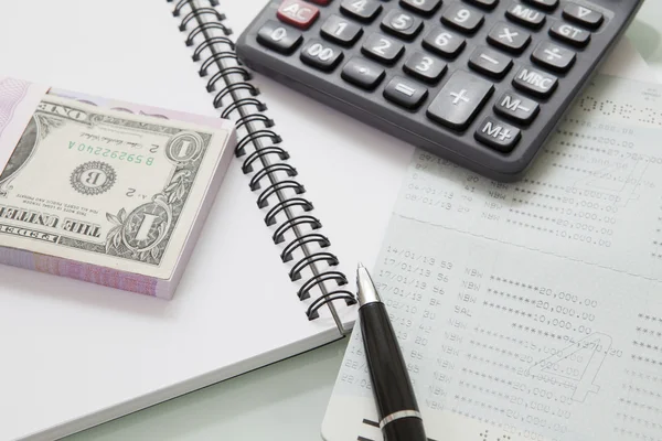 Pila de billetes de banco y calculadora de bolígrafos en el cuaderno de notas —  Fotos de Stock