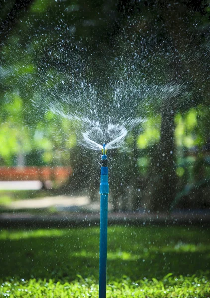 Salpicaduras de agua del uso de aspersores de jardín al aire libre para la frescura — Foto de Stock