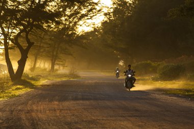 RAYONG THAILAND-AUGUST 11 : unidentified people riding motorcycle along dusty road in undevelopment rural district of Rayong province eastern of thailand on august11,2014 in RayongThailand clipart