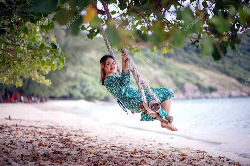 asian younger woman relaxing on swing  at beach