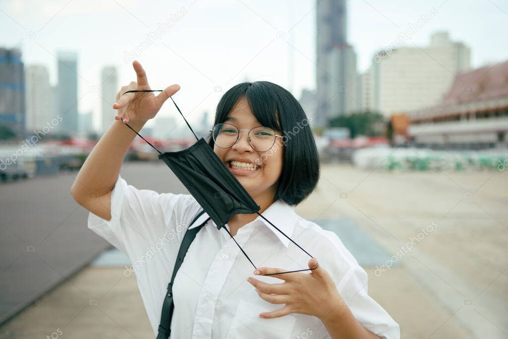 cheerful asian teenager with protection face mask in hand 
