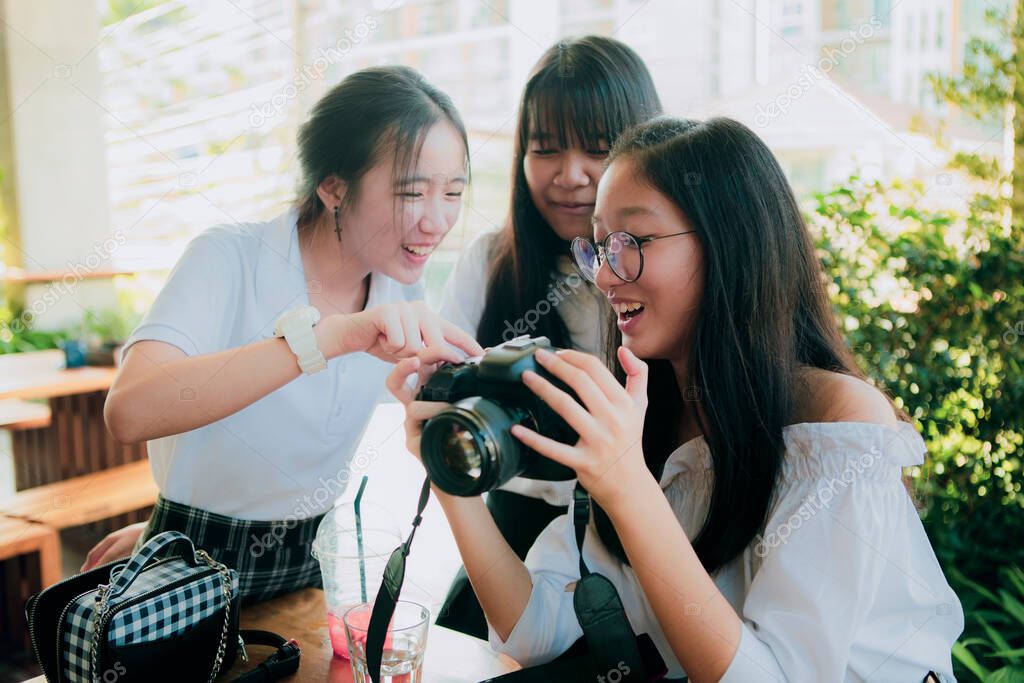 group of asian teenager looking image on dslr camera screen with happiness face