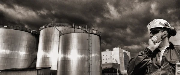 日落时分石油工人和燃料存储塔 — 图库照片