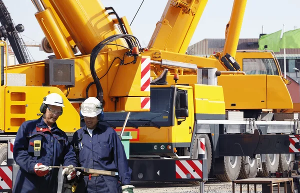 Building workers and giant mobile cranes — Stock Photo, Image