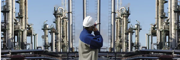 Oil worker pointing at giant oil and gas industry — Stock Photo, Image