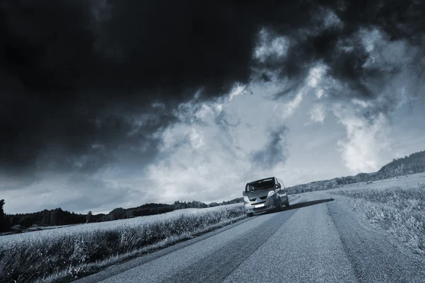 Carro, suv dirigindo sob um céu tempestuoso — Fotografia de Stock