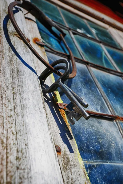 古い壊れた窓に掛かっているアンティークの鍵リング — ストック写真