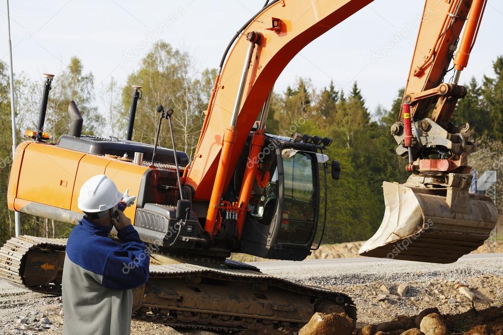 Industry worker directing large bulldozer and driver