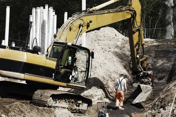 Digger and site worker in action — Stock Photo, Image