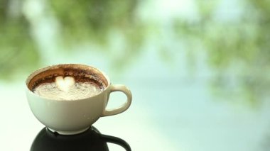 Kahve fincanı cam sehpanın üzerinde. Bulanık yaprak yansıma arkaplanı.