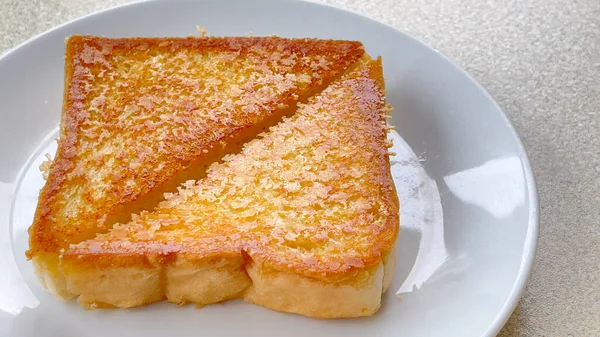 白い小麦粉から作られたトーストパンの2枚の三角形のスライスと白いテーブルの背景に白いプレートにチェダーチーズのスライス — ストック写真
