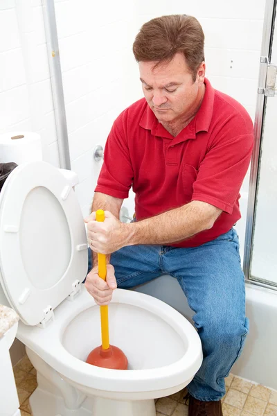 Mann benutzt Kolben auf verstopfter Toilette — Stockfoto