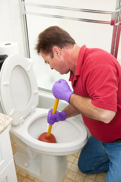 Hombre usando émbolo en el inodoro — Foto de Stock