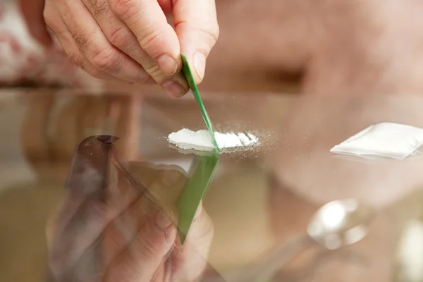 Snijden cocaïne op glazen tafel — Stockfoto