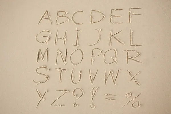 The alphabet written in sand on a beach. — Stock Photo, Image