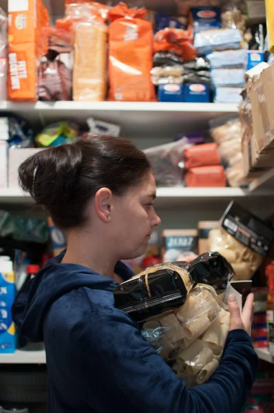 Endişeli kadın kileri erzak ve makarna ile dolduruyor.