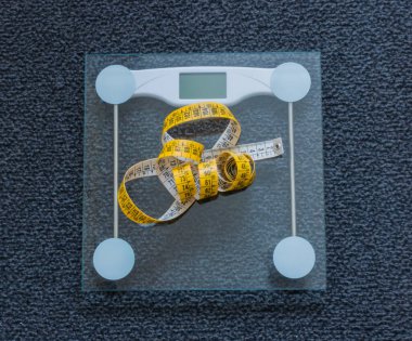 Cam ölçekte mezura, arka planda koyu gri halı.