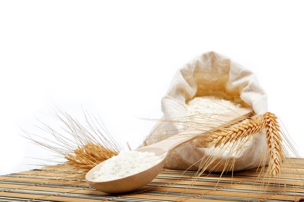 Meel en tarwe graan met houten lepel op een houten tafel. — Stockfoto