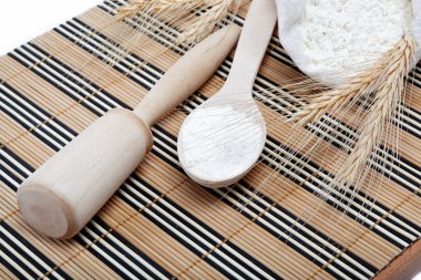 ahşap bir masa üstünde tahta kaşıkla un ve buğday tahıl.