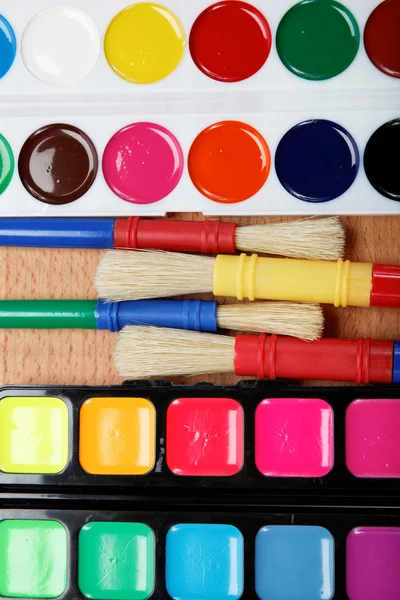 Pintura, paleta e pincéis em uma mesa de madeira . — Fotografia de Stock