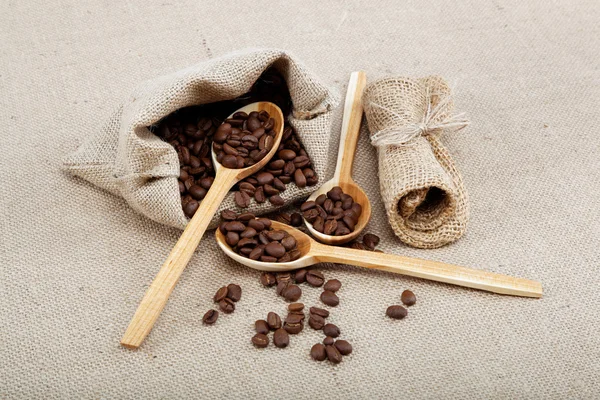 Kaffebönor i en skedar på säckväv. — Stockfoto